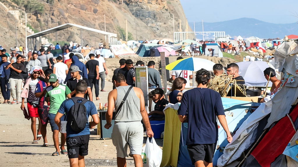 Zona costera e instalaciones provisionales en Ceuta con presencia de vehículos de emergencia.