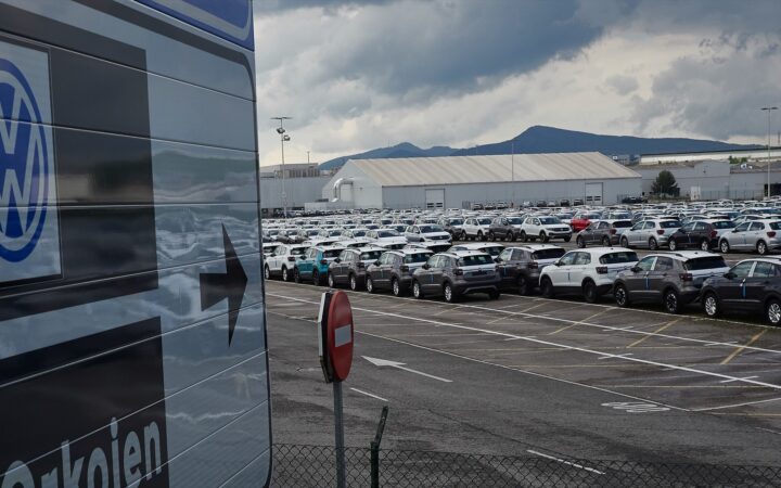 Gráfico financiero descendente y silueta de una fábrica de automóviles representando la crisis de previsiones de Volkswagen