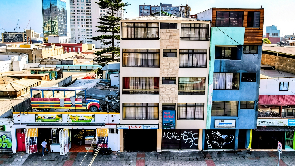 Fotografía aérea de la fachada del Hotel Antofagasta Centro y edificios colindantes en una calle urbana concurrida.