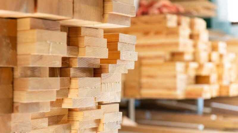 Pilas de tableros y listones de madera cortados y almacenados en un taller o almacén industrial.