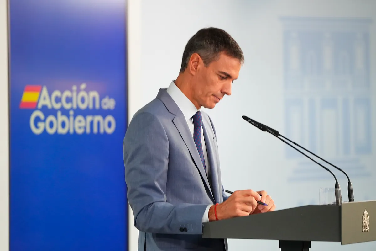 Fotografía editorial de Pedro Sánchez interviniendo en una rueda de prensa institucional con el logotipo de Acción de Gobierno de fondo.