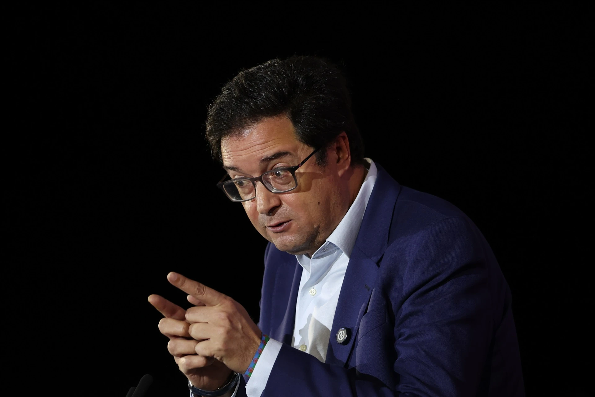 Retrato fotográfico del ministro Óscar López con traje azul y camisa blanca, gesticulando con las manos durante una intervención.